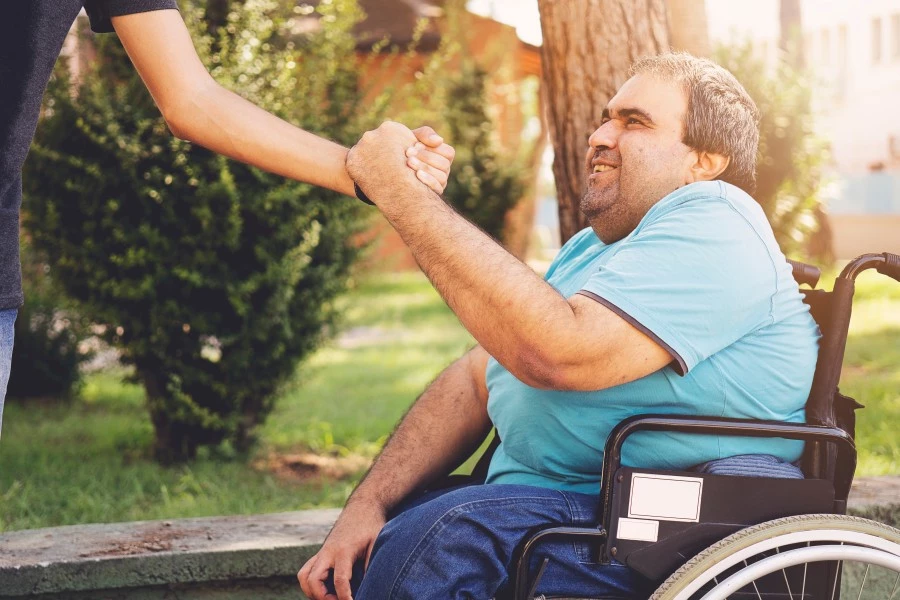 Man with disability in wheelchair shaking the hand of another person