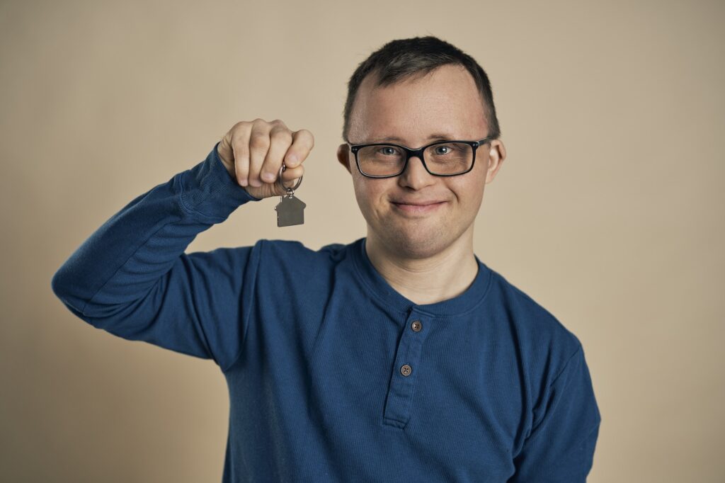 Caucasian man with down syndrome holding new home symbol