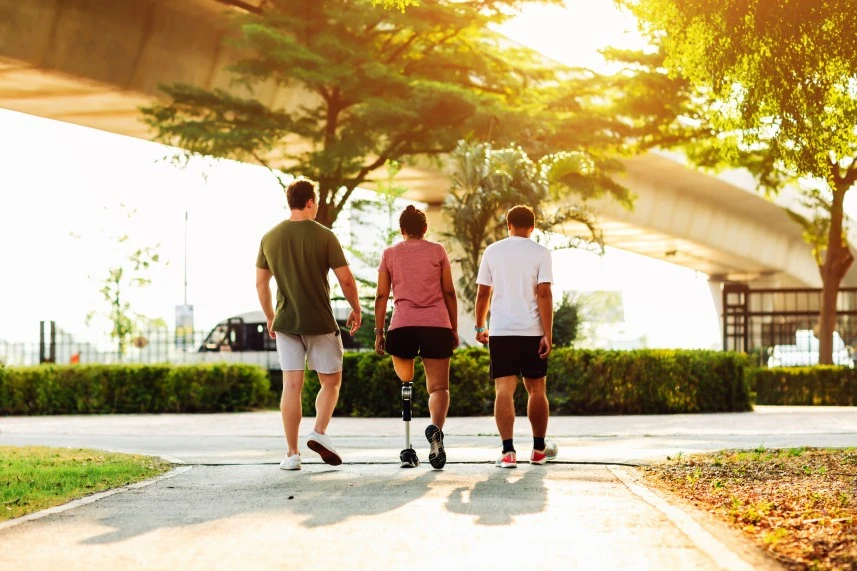 Three friends, one with disability, walking in park together